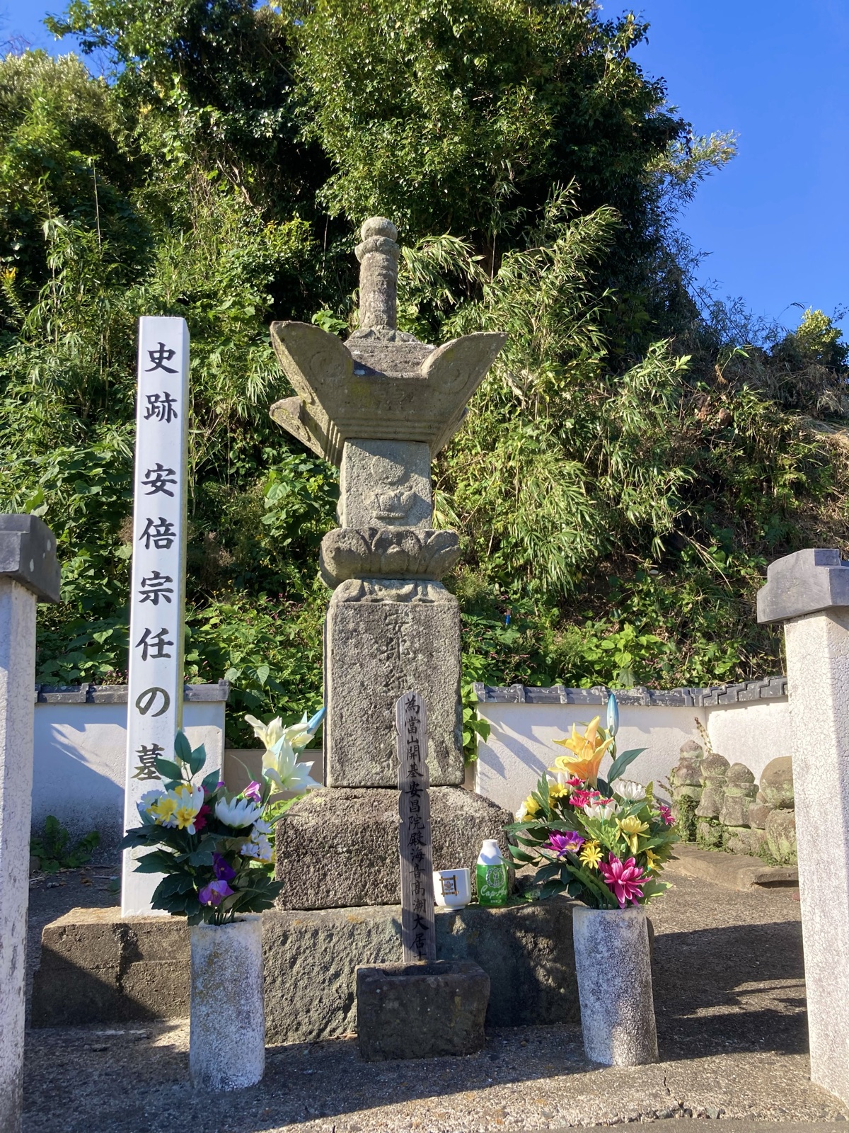 筑前宗像・大島に伝わる安倍宗任の墓。石塔の傍らに標柱が立ち、花が供えられている。