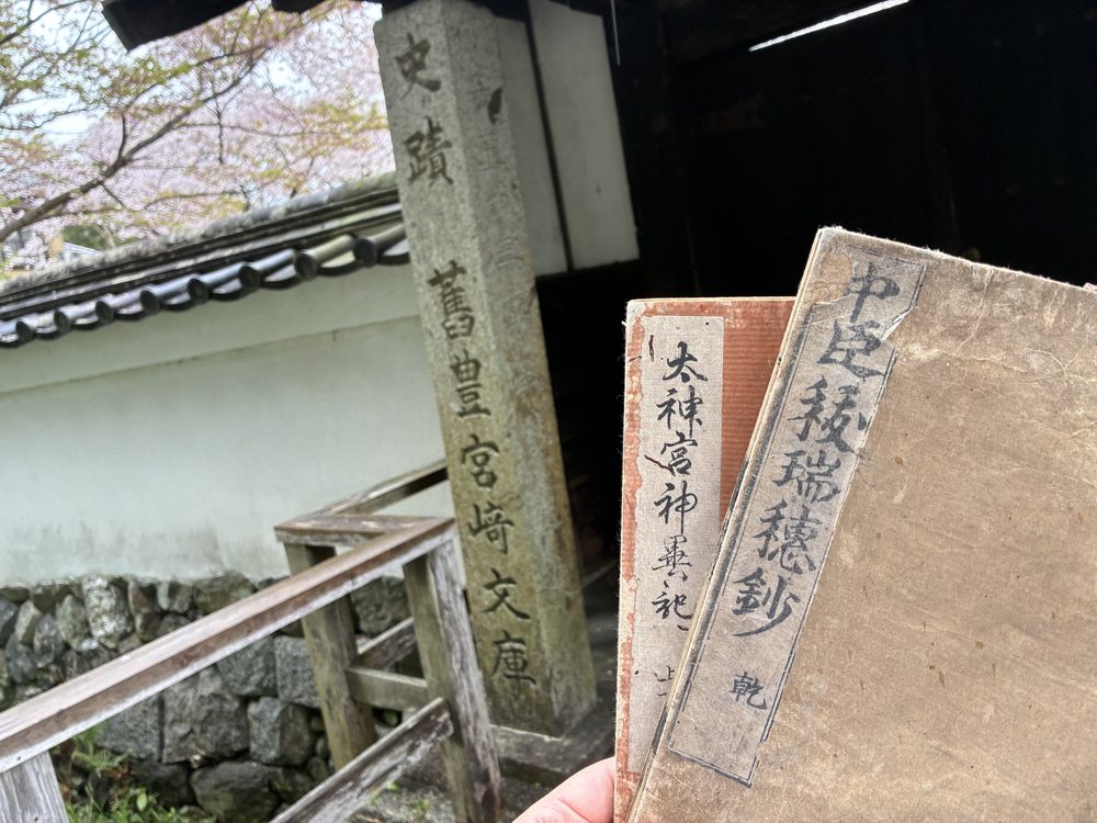 史蹟・舊豐宮崎文庫の石柱の前にて 所蔵の典籍と共に